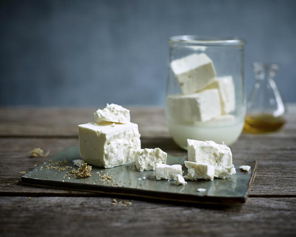 Pieces of feta cheese on a plate and in a glass